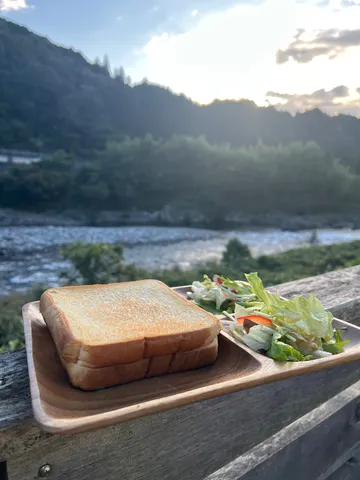 川辺のトーストとサラダ、夕陽が染める山。