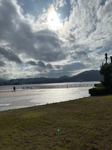 曇り空に差し込む光、水辺の散歩道