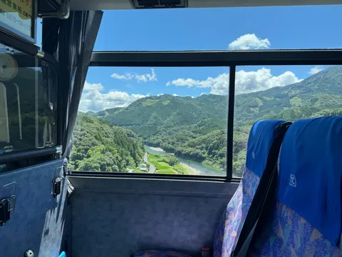 バス窓から見た緑の山と川