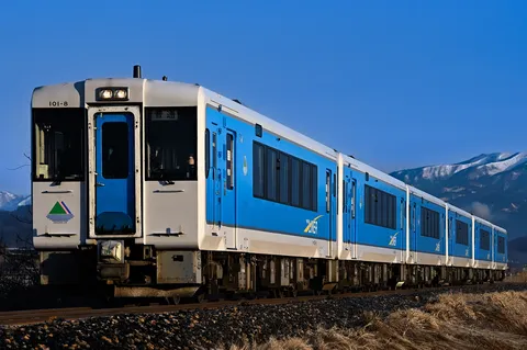 澄んだ空の下、走る青い列車