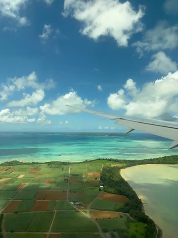 飛行機窓の先、碧い海と豊かな大地