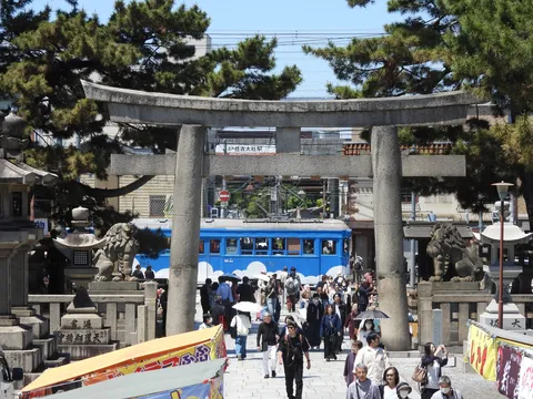 鳥居と青い電車、賑わう参道