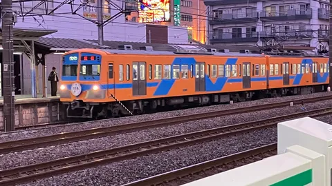 夕暮れに佇むオレンジの電車