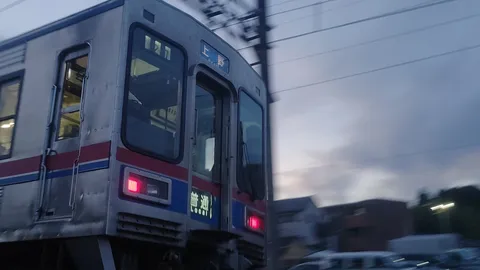 夕闇迫る線路を走る電車