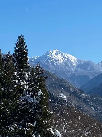 冬空に浮かぶ月と雪化粧の山