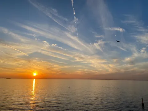 水平線に沈む夕日と飛ぶ飛行機