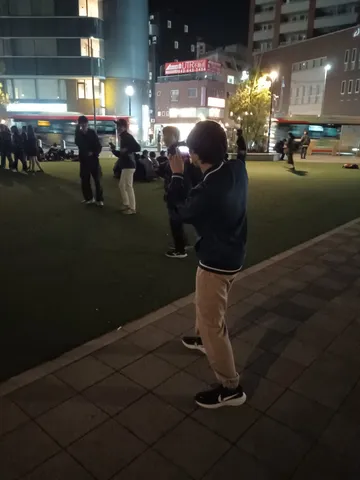 夜の街角、スマホを構える人