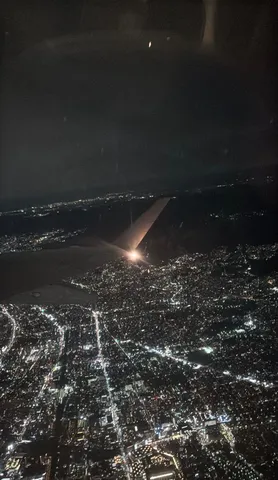 夜景と飛行機の翼、地上を照らす光