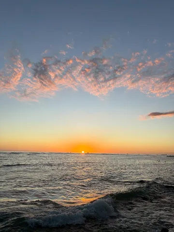 水平線に沈む夕日とオレンジの雲