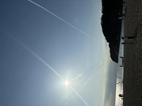 夕日に輝くビーチと飛行機雲
