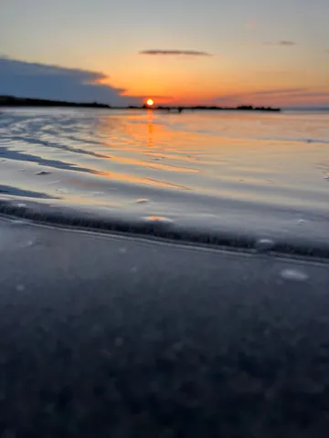 水面が語る夕暮れ、静寂の浜辺