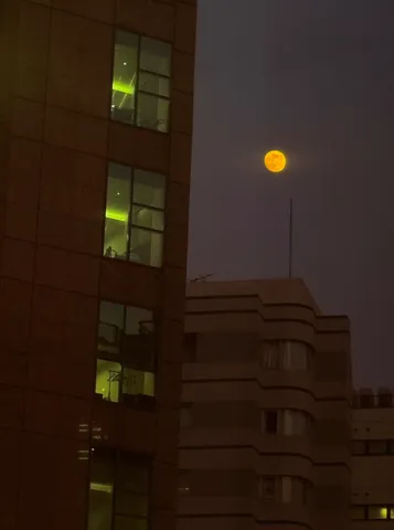 夜空のオレンジ月と緑の光