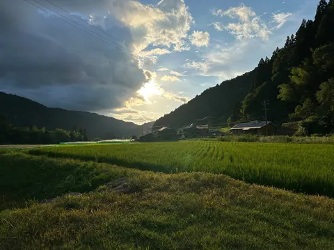 雲間から差し込む光と田園風景