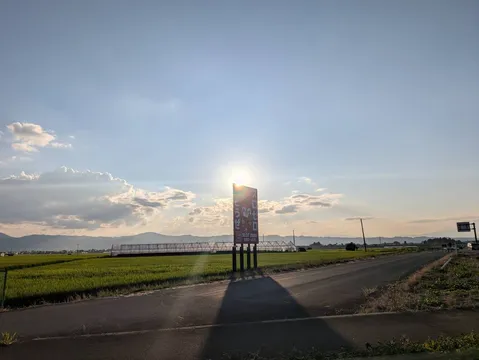 夕暮れに染まる田園と看板