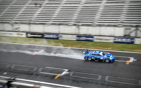 雨煙を纏い疾走するレーシングカー