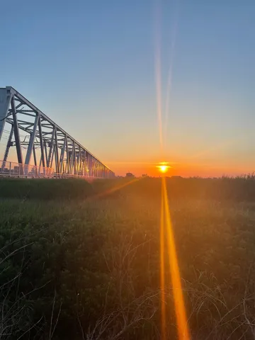 夕暮れの草原と鉄橋の影