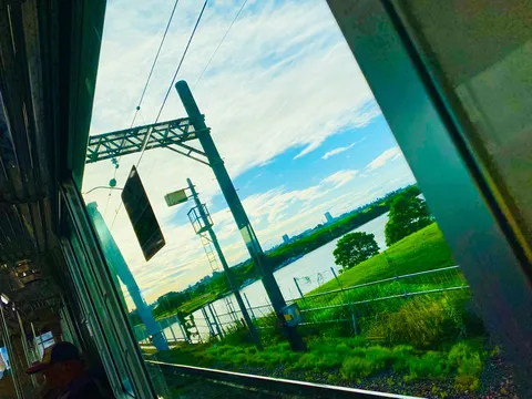 電車の窓から見える、水辺と空のコントラスト