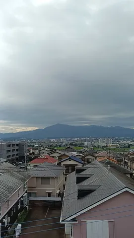 雨雲の下の街並みと山々