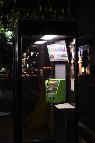 夜のガラス越しの緑電話