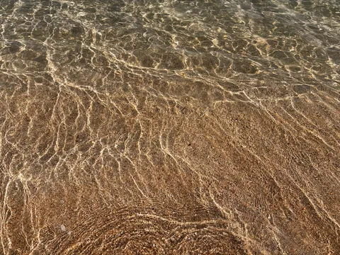 水面の光がきらめく砂浜