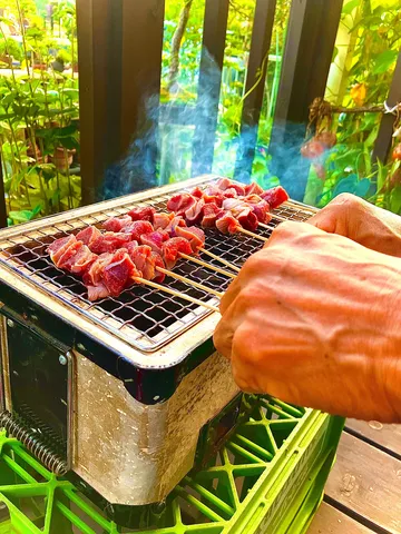煙立つ串焼き、豊かな緑の中で