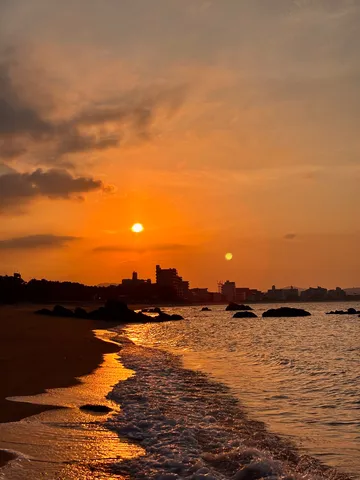 オレンジ色の波打ち際、空と海が溶け合う夕景