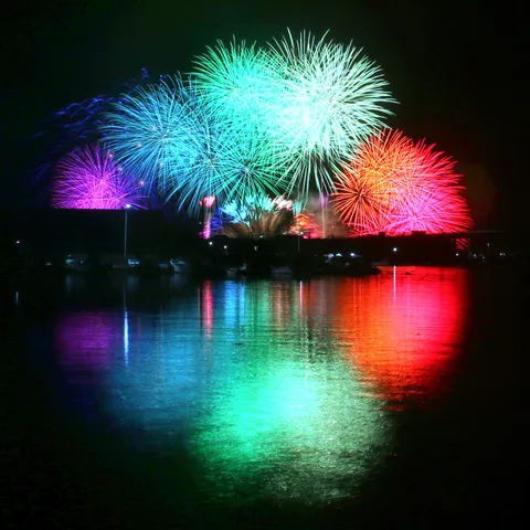 夜空に咲く光の花、水面に映る幻想世界