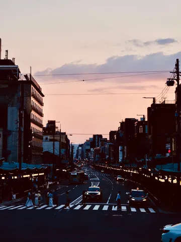 夕暮れ時の都会、交差点を渡る人々