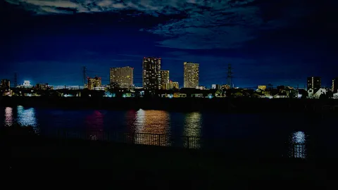 都会の夜景に水面が灯す光の帯