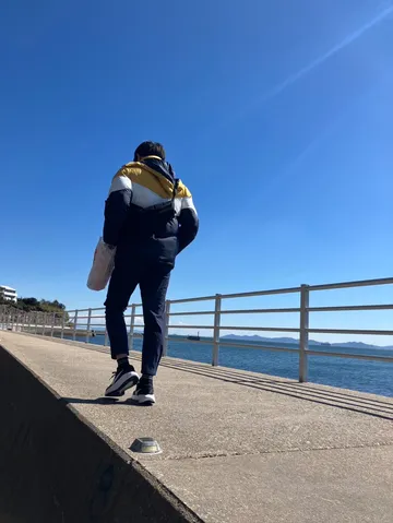 青空と海辺を歩く人