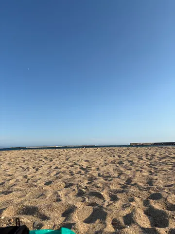 砂浜に刻まれた足跡、広がる青い空