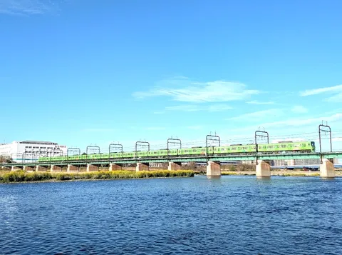 川を渡る緑の電車、青い空