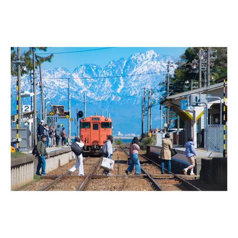 オレンジの電車と雄大な雪山