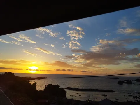 夕陽に染まる水平線と雲のカーテン