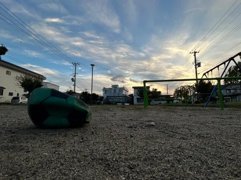 夕暮れ公園に転がる緑のボール