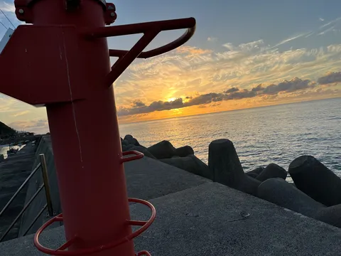 夕陽と灯台、静かな港の夜明け