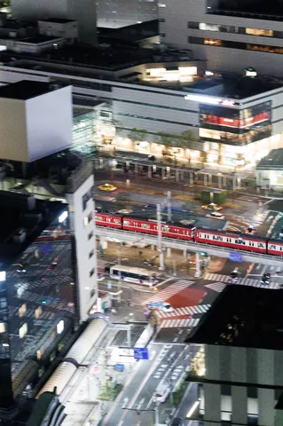 都会の夜景を駆け抜ける赤い電車