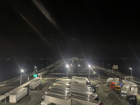 夜の海を渡る巨大な橋とトラック群