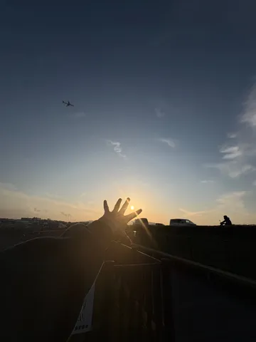夕陽と飛行機、指の隙間