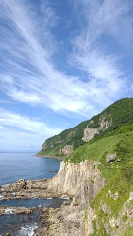 灯台の灯る緑の山と断崖絶壁