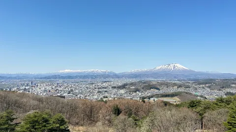 青空の下、雪山を望む街並み