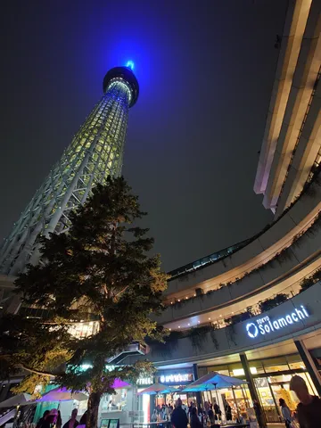 夜空にそびえる青い光と都会の賑わい