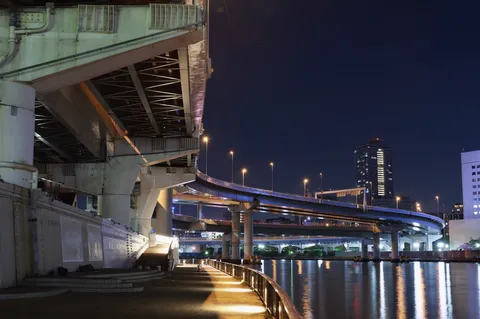 夜の水辺を走る高架と街灯