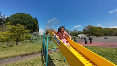 初夏の公園、笑顔で滑り台