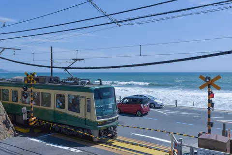 海沿い列車と踏切、青い空のコントラスト