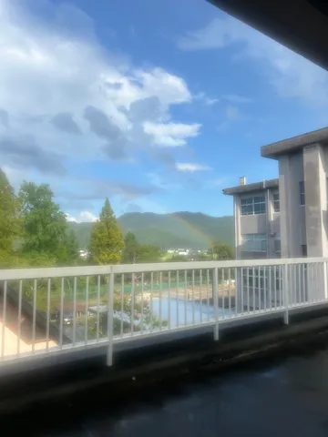 虹が彩る、曇り空と学校の風景