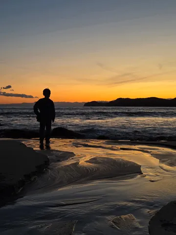 夕焼けの海辺と静かな人影