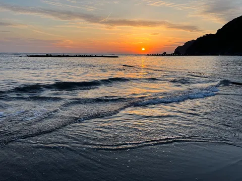 波間に沈む夕日、静寂の海辺
