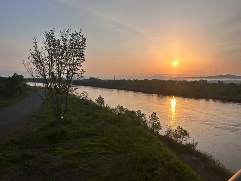 水面を照らす朝陽と緑の丘