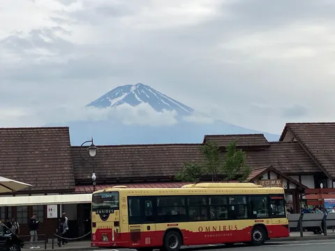 雲間から顔を出す富士山とレトロバス